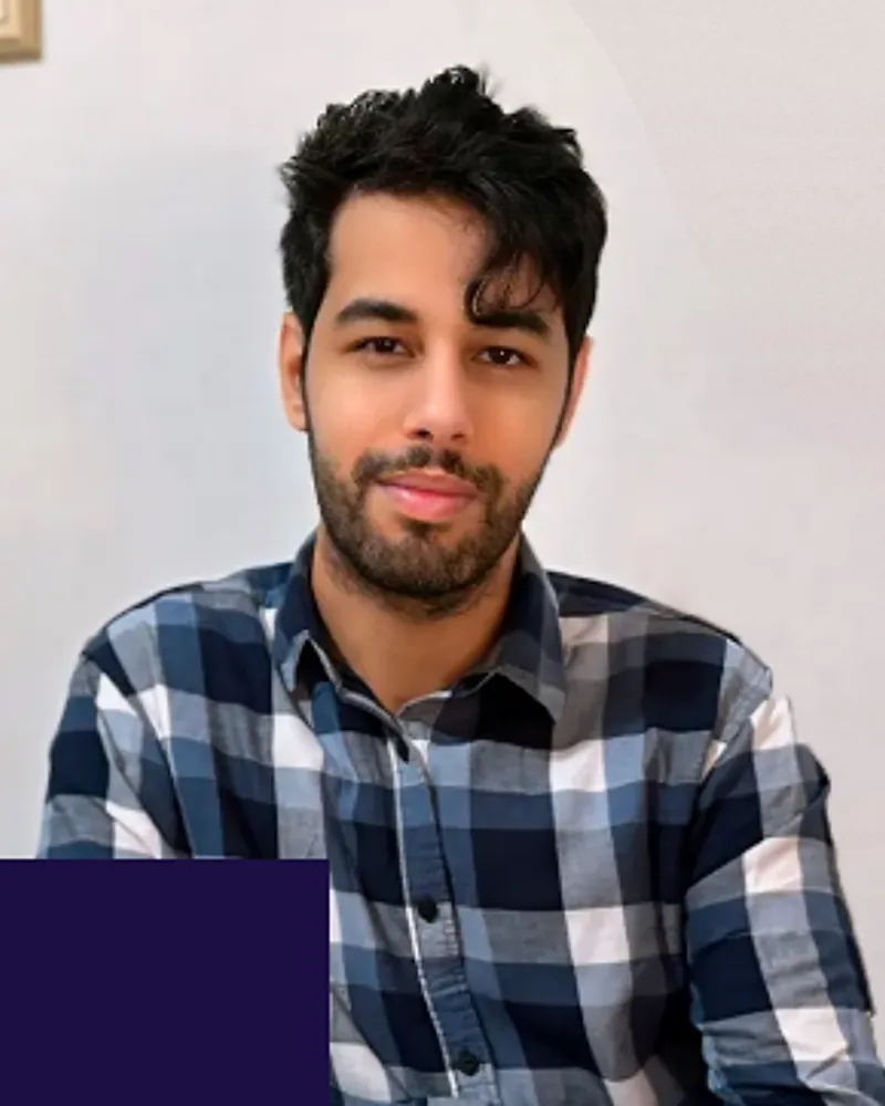 João Raphael Couto Melo, psicólogo, de camisa xadrez azul, com um leve sorriso